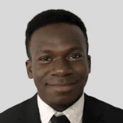 A man wearing a dark suit, white shirt, and black tie smiles at the camera against a plain light gray background, reflecting confidence in innovative BIM and AI solutions.