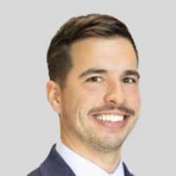 A man in a suit and tie smiles at the camera against a plain light gray background, embodying confidence in fields like AI and BIM.