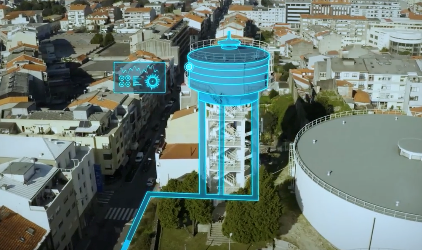 A digital overlay on an aerial view of an urban area highlights a water tower and accompanying infrastructure, emphasizing technical features with a holographic display using OpenFlows for advanced hydraulic modeling.