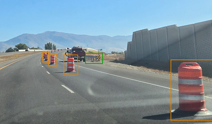 Traffic cones line a U.S. Interstate Highway, with a vehicle parked in the distance and mountains visible under the clear sky. This well-maintained stretch highlights the importance of digital infrastructure movement in managing roadway assets efficiently.
